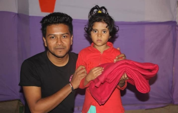 A child receiving a warm blanket during Alor Uday Foundation's winter distribution